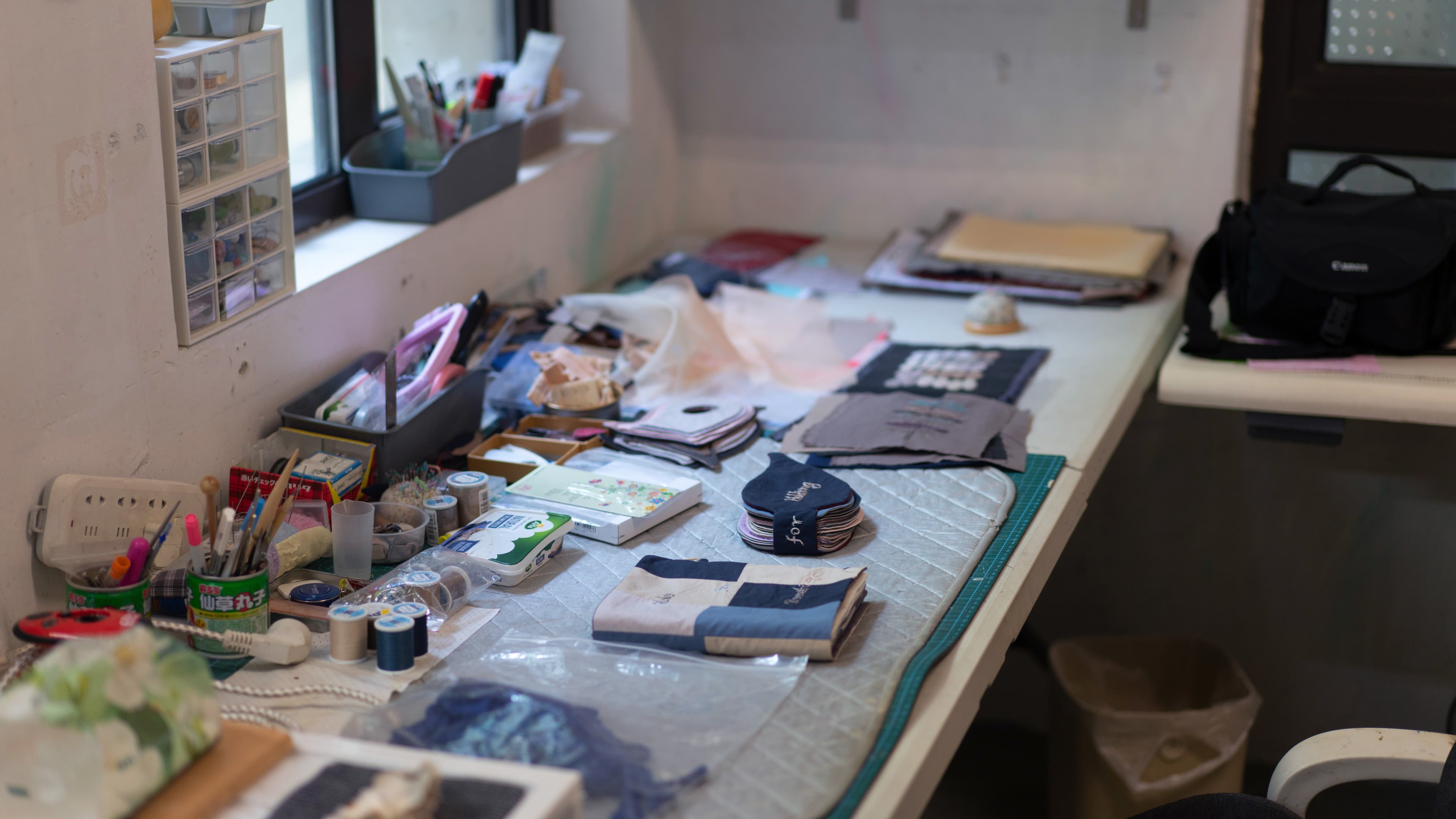 Fabric, thread, and tools spread across a worktable in Yuyu Wang's studio